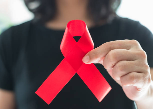 aids red ribbon on woman's hand support for world aids day and national hiv/aids and aging awareness month concept - world cancer day imagens e fotografias de stock