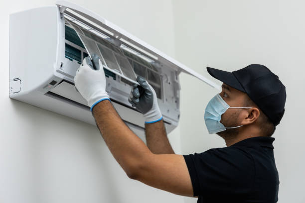 Air conditioner service indoors. Air conditioner cleaning technician He opened the front cover and took out the filters and washed it. He in uniform wearing rubber and mask. stock photo