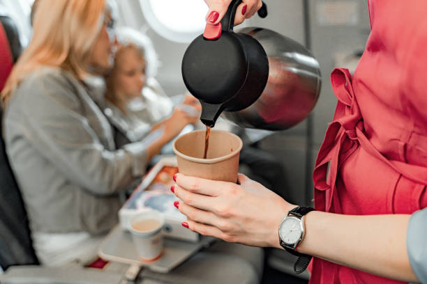 Air hostess is making coffee for passengers Cropped photo of stewardess holding teapot and paper cup stock photo crew stock pictures, royalty-free photos & images