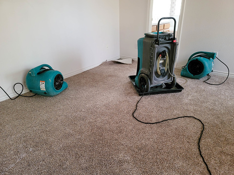 Two air movers and a dehumidifier drying a home.