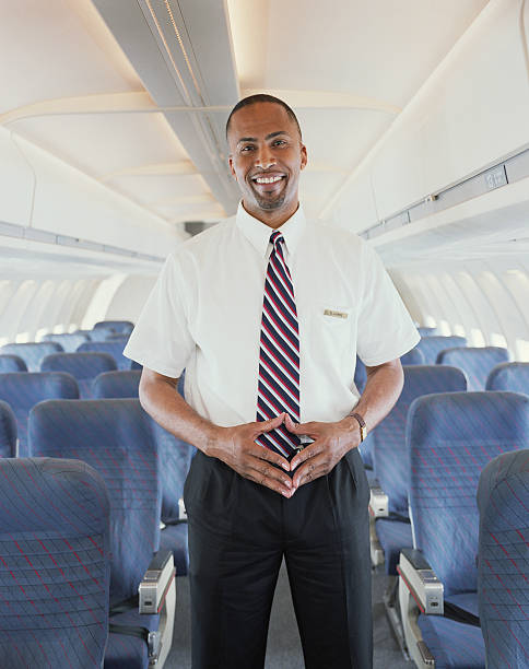 Air steward standing in aisle of aeroplane, smiling, portrait  crew stock pictures, royalty-free photos & images