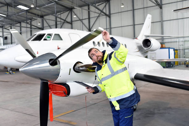 Aircraft mechanic inspects and checks the technology of a jet in a hangar at the airport Aircraft mechanic inspects and checks the technology of a jet in a hangar at the airport aeronautical engineering stock pictures, royalty-free photos & images