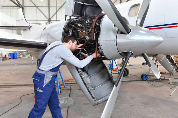 Aircraft mechanic repairs an aircraft engine in an airport hangar Aircraft mechanic repairs an aircraft engine in an airport hangar Aerospace and Aeronautical Engineering stock pictures, royalty-free photos & images