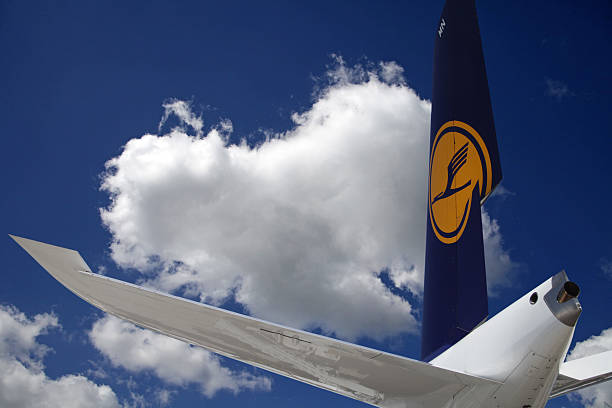 Airliner tail wing in blue summer sky with puffy clouds stock photo