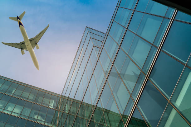 Airplane flying above office building. Skyscraper modern building. Finance business trip. Glass windows. Aviation business after coronavirus vaccine injection. Plane flying above futuristic building. stock photo