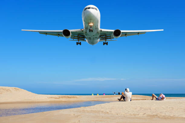 Airplane landing above Beautiful tropical sea with white sand on the beach and clear blue sky people take a photo airplane at phuket thailand image for summer season and travel background. stock photo