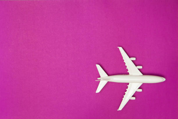 Airplane model. White plane on purple background. Travel vacation concept. Summer background. Flat lay. stock photo