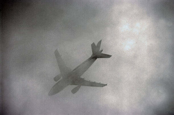 Airplane passing in low clouds stock photo