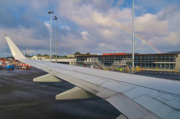 Airplane wing with rainbow. Hobart Airport building is in the background stock photo