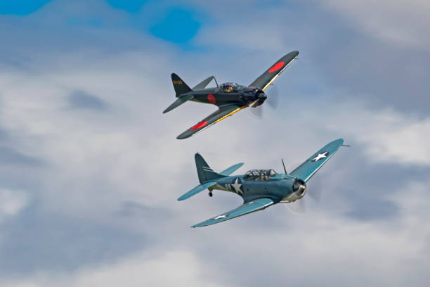Airplanes Mitsubishi Zero and Dauntless aircraft performing an aerial dog foght during an air show Chino, California,USA- May 7,2017. Airplanes flying in an aerial dog fight during the 2017 Planes of Fame Air Show in Chino, California. The Planes of Fame Air Show features 3 days of military rare and vintage aircraft performing and flying for the general public. ww2 american fighter planes stock pictures, royalty-free photos & images