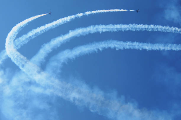 Airplanes with smoke trails Two airplanes with smoke trails in the blue sky during air show airshow stock pictures, royalty-free photos & images