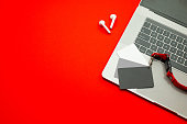 istock Paris, France - Jan 7, 2022: AirPods wireless Bluetooth headphones created by Apple Computers and of MacBook Pro laptop with gray coupon card on red background 1386815406