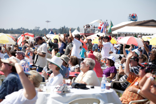 Abbotsford, Canada - August 11, 2012: This image shows a group of people enjoying the airshow in Abbotsford, Canada.  Some are seated at tables and others are standing to get a better view.