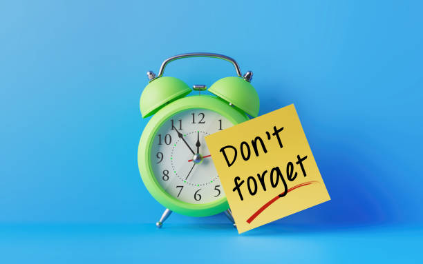 Alarm Clock And A Yellow Post It Note Over Blue Background Green alarm clock with a yellow post it note attached over bright blue background. Don't Forget writes on post it note is blank. Reminder concept. Horizontal composition with copy space. deadline stock pictures, royalty-free photos & images