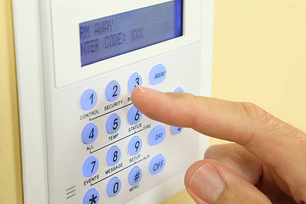 Alarm System Keypad Close up of a security alarm keypad with person arming the system. burglar alarm stock pictures, royalty-free photos & images
