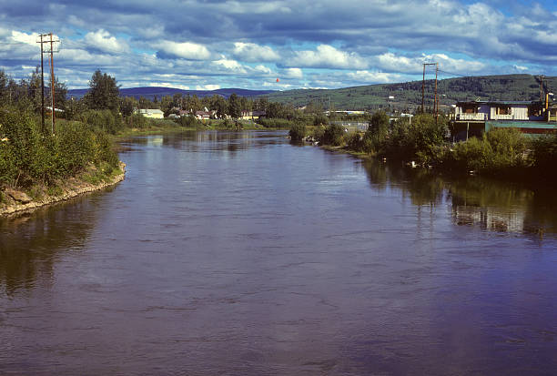 Alaska river running through small town An Alaska river with houses next to the bank of the river. Beautiful clouds fill the sky. hearkencreative stock pictures, royalty-free photos & images
