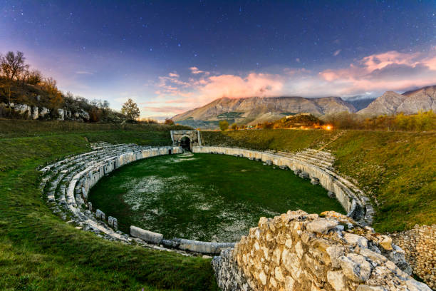 Alba Fucens (Italy) - An evocative Roman archaeological site with amphitheater, in a public park in front of Monte Velino mountain with snow, Abruzzo region, central Italy stock photo