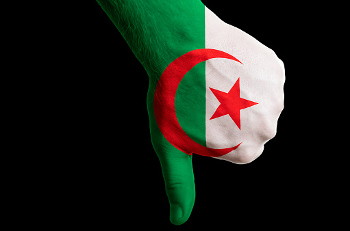 Hand with thumb down gesture in colored algeria national flag as symbol of negative political, cultural, social management of country