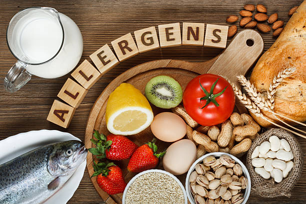 Allergy food Allergy food concept. Allergy food as almonds, milk, pistachios, tomato, lemon, kiwi, trout, strawberry, bread, sesame seeds, eggs, peanuts and bean on wooden table allergy stock pictures, royalty-free photos & images