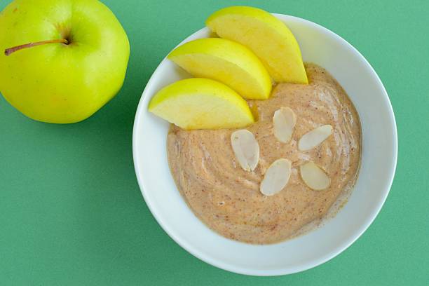 Almond butter yogurt with sliced apple in a bowl Almond butter yogurt with sliced apple in a bowl. Top view image almond butter stock pictures, royalty-free photos & images