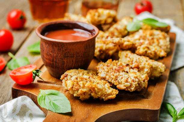 almond crusted chicken tenders with ketchup on a wood background almond crusted chicken tenders with ketchup on a wood background. toning. selective Focus affectionate stock pictures, royalty-free photos & images