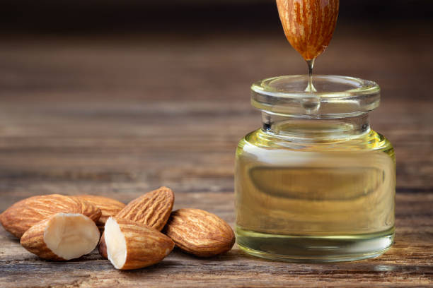 Almond oil Almond oil in bottle and nuts on wooden table almond stock pictures, royalty-free photos & images