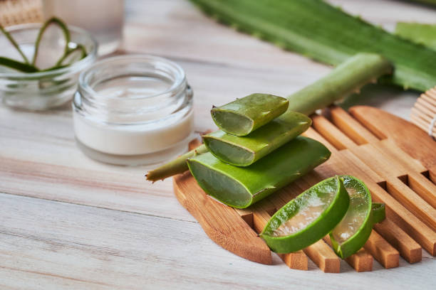 Aloe vera slices and moisturizer on a wooden table. Beauty treatment concepts stock photo