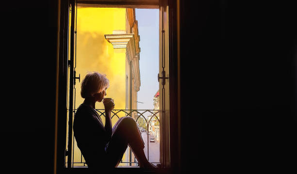 Alone Woman Silhouette Alone Woman Sitting on Window and Drinks Tea or Coffee tea hot drink stock pictures, royalty-free photos & images