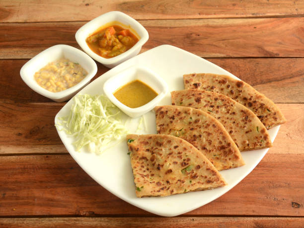 Aloo Paratha or Indian Potato stuffed Flatbread. Served with fresh curd, veg gravy and salad. isolated over a rustic wooden background, selective focus Aloo Paratha or Indian Potato stuffed Flatbread. Served with fresh curd, veg gravy and salad. isolated over a rustic wooden background, selective focus chapatti stock pictures, royalty-free photos & images