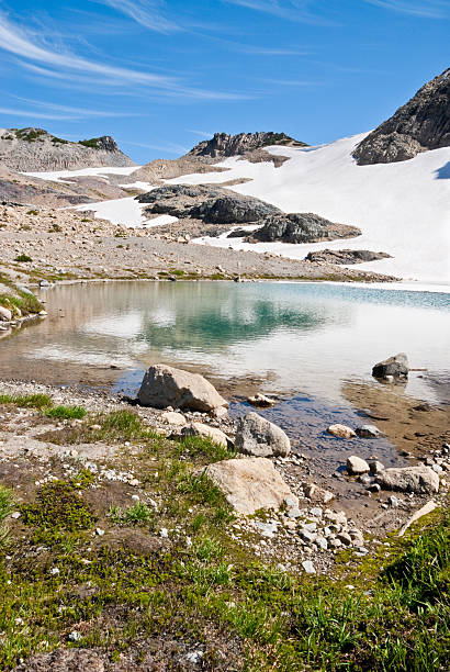 Alpine Lake Below Panhandle Gap The 93 mile Wonderland Trail encircles Mount Rainier. The trail crosses many ridges and valleys, gaining and losing 22,000 feet of elevation along the way. The Wonderland Trail was built in 1915 and in 1981 was designated a National Recreation Trail. This scene of an alpine tarn or pond was photographed near Panhandle Gap, the highest point on the trail at 6800 feet. The Wonderland Trail is in Mount Rainier National Park, Washington State, USA. jeff goulden mount rainier national park stock pictures, royalty-free photos & images