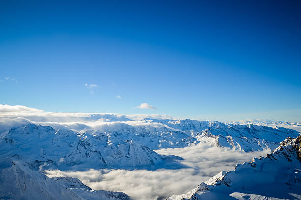 Alps snow covered Panorama of the Alps. Some snow-capped peaks rising above the clouds on a sunny day. Ski area on the Kitzsteinhorn Glacier in Kaprun, Salzburg, Austria. Copy space on the clear blue sky in the background. osttirol stock pictures, royalty-free photos & images
