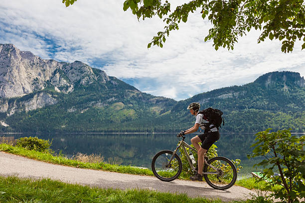 Altaussee lakeside biking A young, female mountainbiker on her ride lakeside the scenic Lake Altaussee in the Ausseerland Region, Styria, Austria. ausseerland stock pictures, royalty-free photos & images