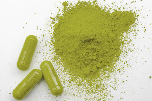 Alternative medicine, herbal pain management and opioid withdrawal treatment concept theme with a pile of green kratom powder and capsules or pills isolated on white background Alternative medicine, herbal pain management and opioid withdrawal treatment concept theme with a pile of green kratom powder and capsules or pills isolated on white background kratom stock pictures, royalty-free photos & images