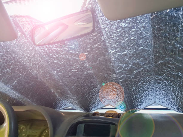 couvre-lit en aluminium sur le pare-brise de la voiture pour la protéger de la chaleur et du soleil à l’intérieur. - parasol photos et images de collection