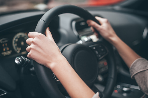 Close-up of female hands on steering wheel while driving a car