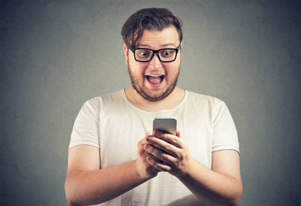 Amazed man with phone reading news Excited chubby man in glasses reading news on smartphone and screaming with surprise fat man looks at the phone stock pictures, royalty-free photos & images