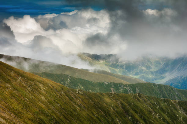 Photo of Amazing landscape of summer mountains. View of fog and low clouds over Fagaras Mountains are the highest mountains of the Southern Carpathians. Romania. Travel background.