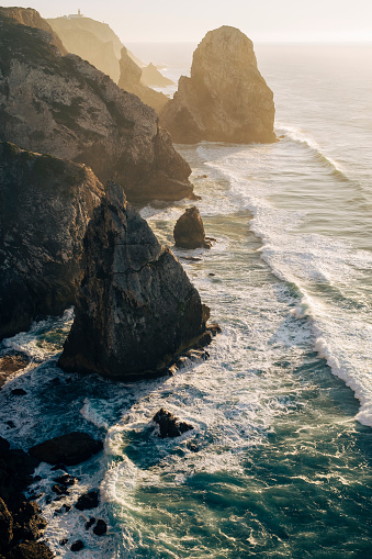 Amazing view of the cliffs and surf in the Atlantic Ocean at sunset, Miradouro da Praia do Caneiro, Portugal.