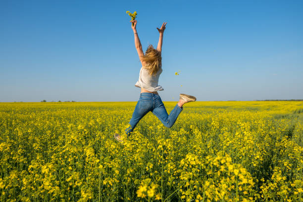 Amazing young woman, blonde jumping and having fun in a field stock photo