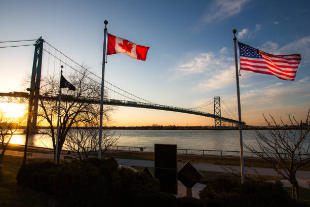 The Ambassador Bridge links Detroit, Michigan, USA with Windsor, Ontario, Canada.  It is one of the busiest trade routes in North America.  This photo depicts the bridge, as seen from Windsor.   The national flags of the USA and of Canada are notable in the foreground.