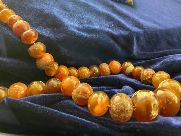 Amber. Beads made from natural yellow brown amber mineral on a white background. Fashionable jewelry amber beads from round and oblong beads. Sun stone as a jeweler raw material. Frozen Resin Fossil Amber. Beads made from natural yellow brown amber mineral on a white background. Fashionable jewelry amber beads from round and oblong beads. Sun stone as a jeweler raw material. Frozen Resin Fossil. fossilized pitch stock pictures, royalty-free photos & images