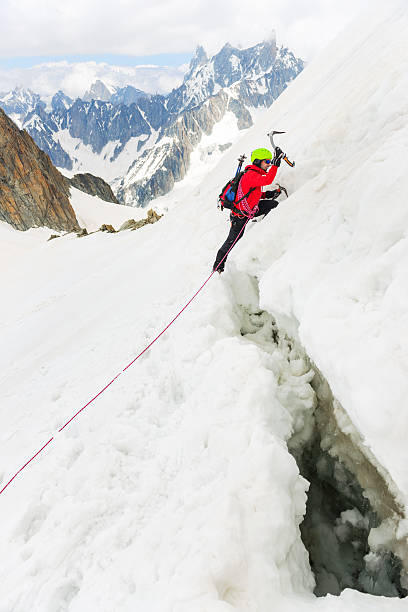Ambition Force Hiker working his way up on a slippery snow covered mountain with a large crevase under him crevice stock pictures, royalty-free photos & images