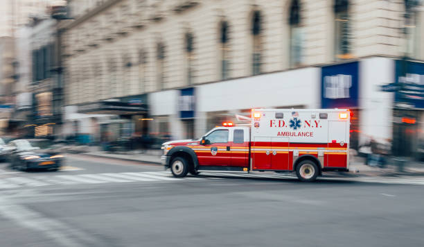 FDNY Ambulance flashing lights siren blasting speed through midtown rush hour traffic in Manhattan. stock photo