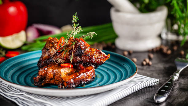 American cuisine. Grilled marinated pork ribs on a blue plate with shrimp and spicy chili in barbecue sauce. Background image. copy space stock photo
