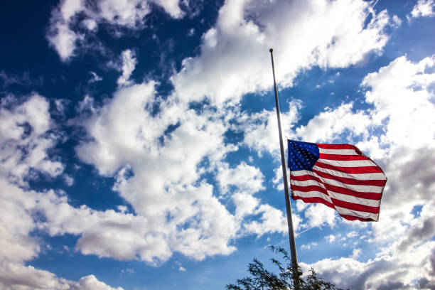 American Flag At Half Mast American Flag At Half Mast Against Blue Sky With Clouds flag at half staff stock pictures, royalty-free photos & images