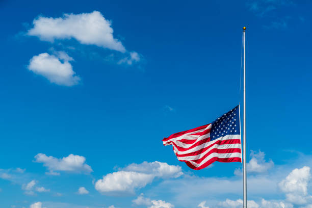 American Flag at half mast American Flag at half mast, blue skies, puffy clouds, patriot, independence day flag at half staff stock pictures, royalty-free photos & images