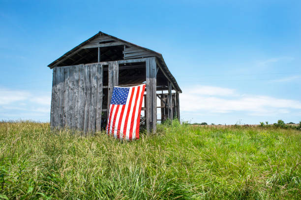 American flag hanging on old gray wood barn stock photo