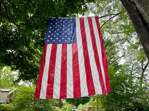 Large American flag hanging over an alley on the 4th of July.