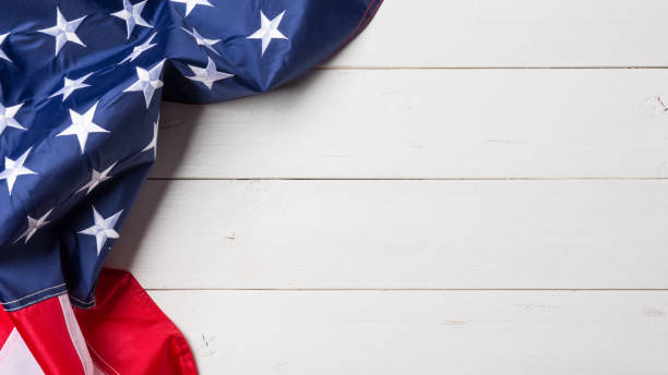 American flag lying on old white wooden background stock photo