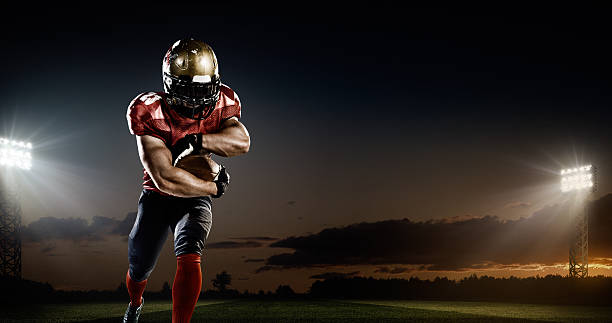 American football in action A male american football player makes a dramatic play. The panoramic view of stadium is behind him. The sky is dark and cloudy behind him.  The player is wearing generic unbranded american football uniform. The stadium is 3D rendered. american football player stock pictures, royalty-free photos & images